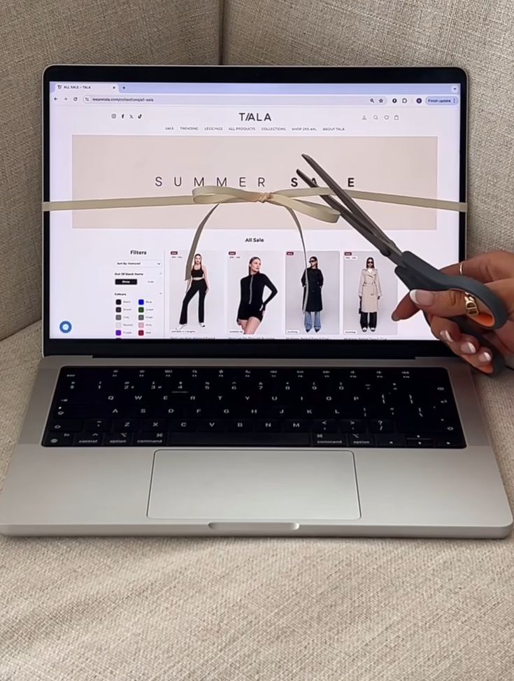 a person is holding scissors over a laptop