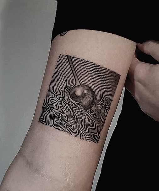 a person with a black and white tattoo on their arm is holding an apple in front of the camera