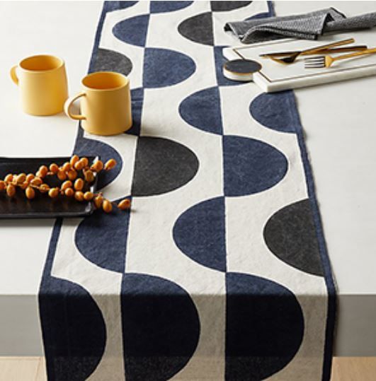 a table topped with a black and white patterned table cloth next to two yellow cups