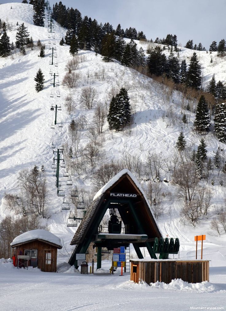 a ski slope covered in snow next to a wooden structure with a sign on it