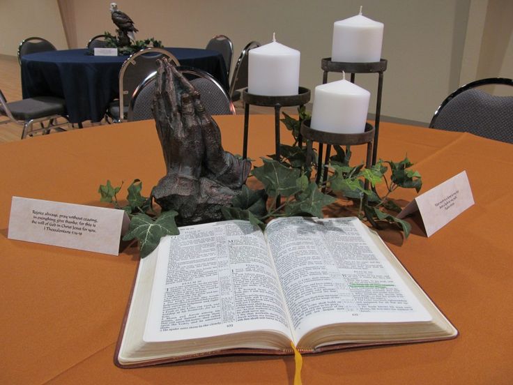 an open book sitting on top of a table next to two candles and a statue