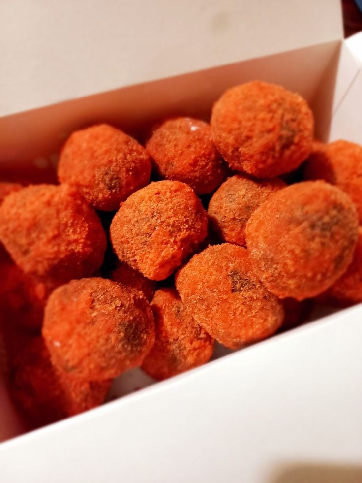 a box filled with orange donuts sitting on top of a table