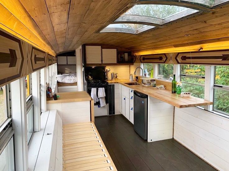 the interior of a tiny house with wood flooring and white walls, windows, and cabinets