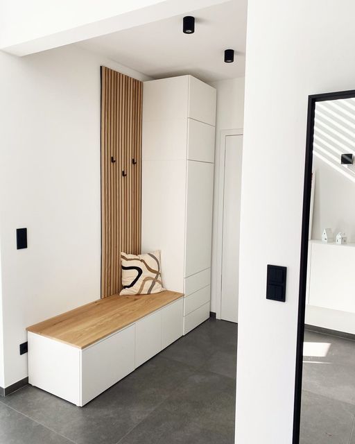 a white room with a wooden bench and mirror