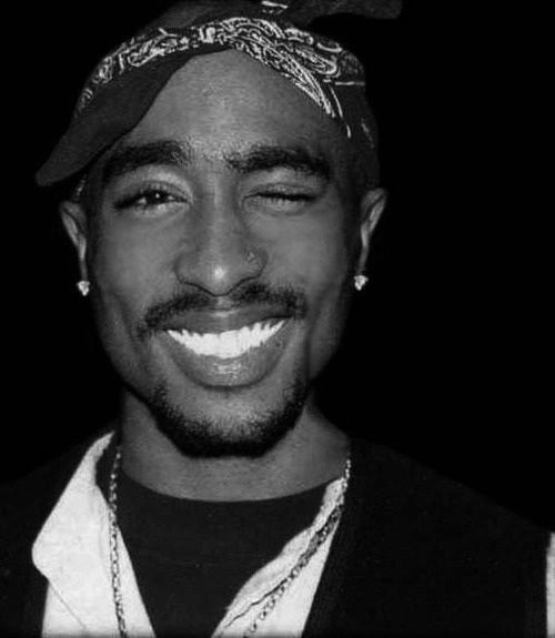 a black and white photo of a man with a bandanna on his head smiling