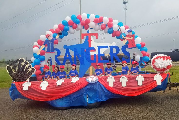 a group of people standing in front of a giant sign with balloons and decorations on it