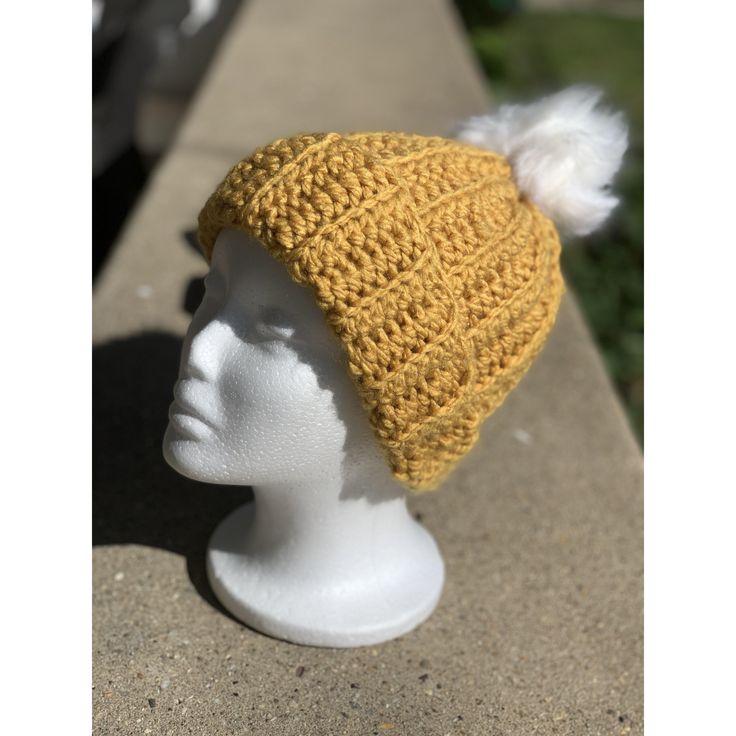 a white mannequin head wearing a yellow knitted hat