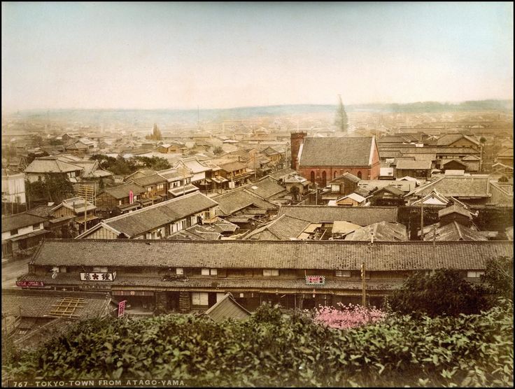 an old photo of a city with lots of buildings and trees in the foreground