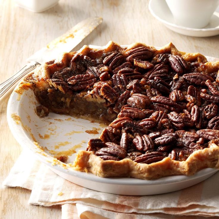 a pecan pie on a white plate with a slice missing from it and two forks next to it