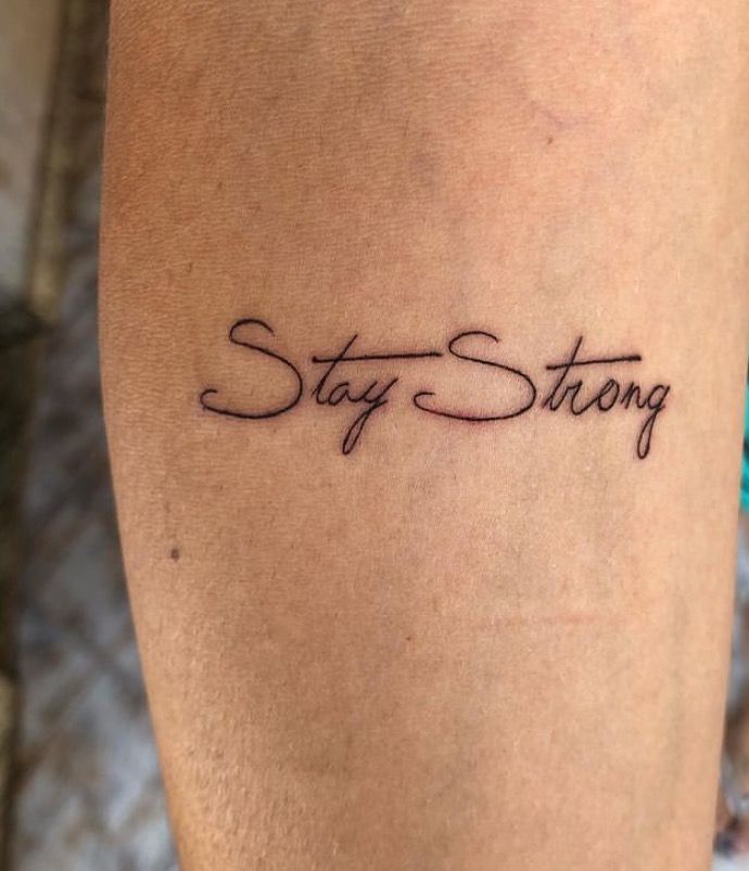 a tattoo saying stay strong on someone's leg