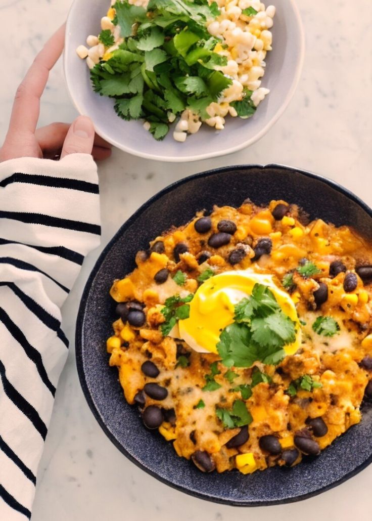 a person is holding a plate with black beans, rice and an egg