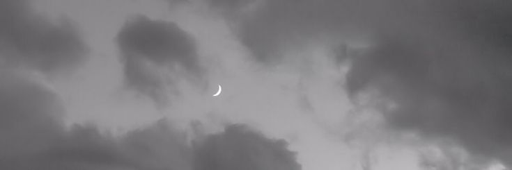 the moon is seen through dark clouds in this black and white photo