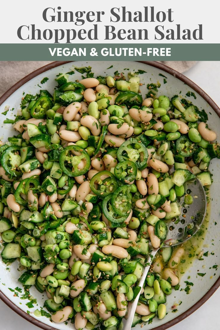 a white bowl filled with bean salad next to a spoon on top of a table