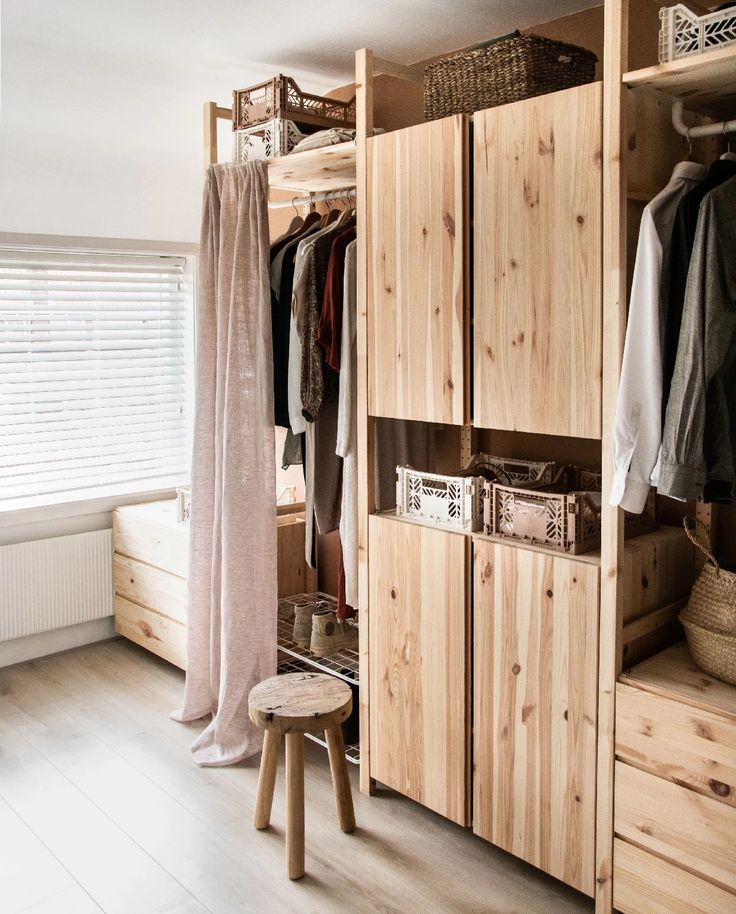 a wooden closet with clothes hanging on the shelves and stools in front of it