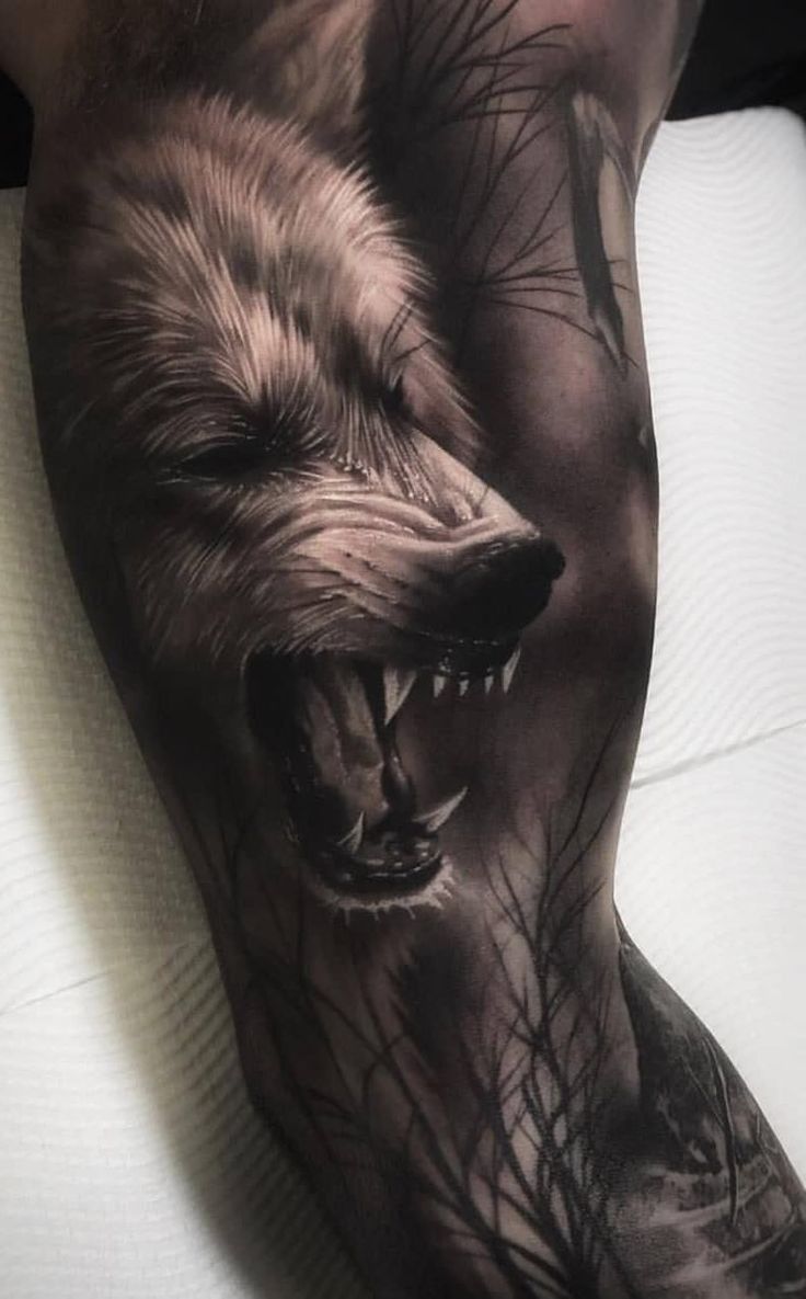 a man's arm with a wolf tattoo on it and his face painted black and white