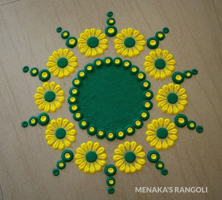 a green and yellow circular design on a wooden surface with circles in the center, surrounded by small yellow flowers