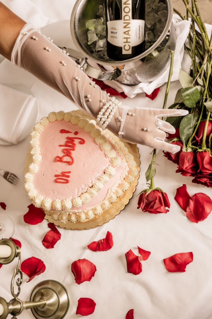 a woman's hand with white gloves is next to a cake and rose petals