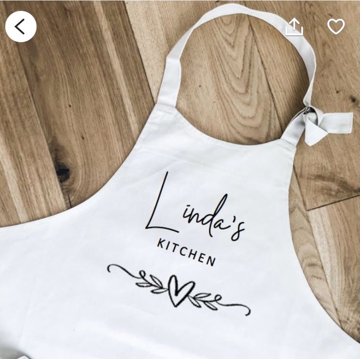 a white apron with the words linda's kitchen on it sitting on a wooden floor