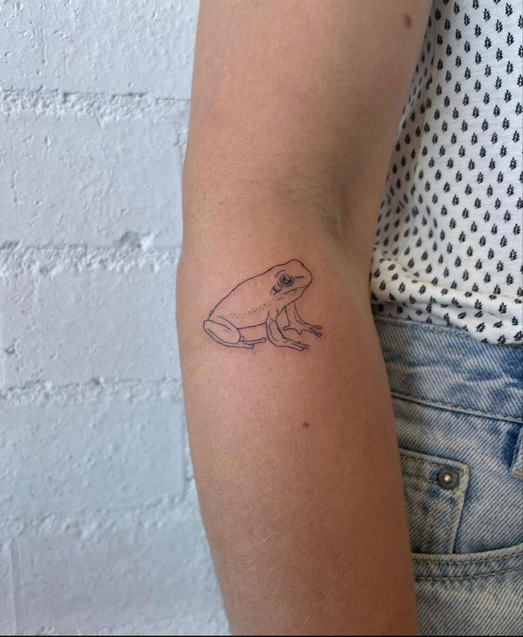 a small frog tattoo on the left arm