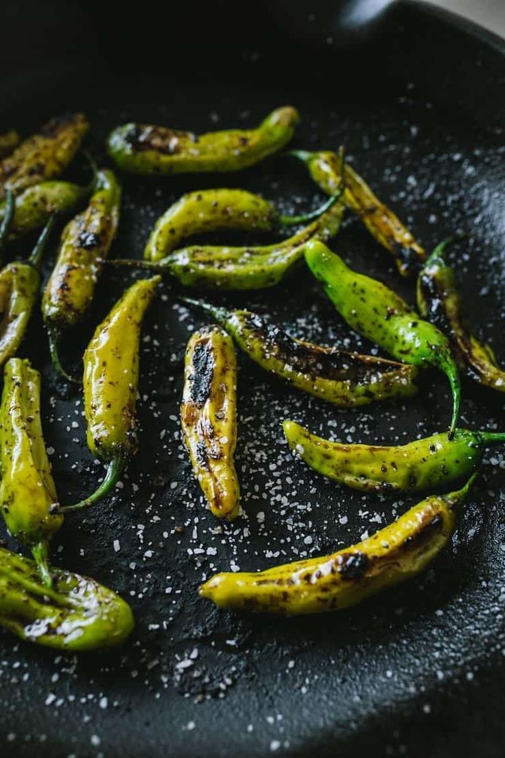 green peppers in a frying pan with salt sprinkled on the top and bottom