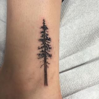 a small pine tree tattoo on the right inner forearm and foot, with black ink