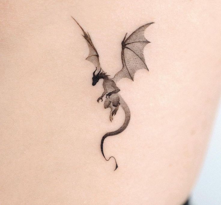 a small dragon tattoo on the back of a woman's shoulder