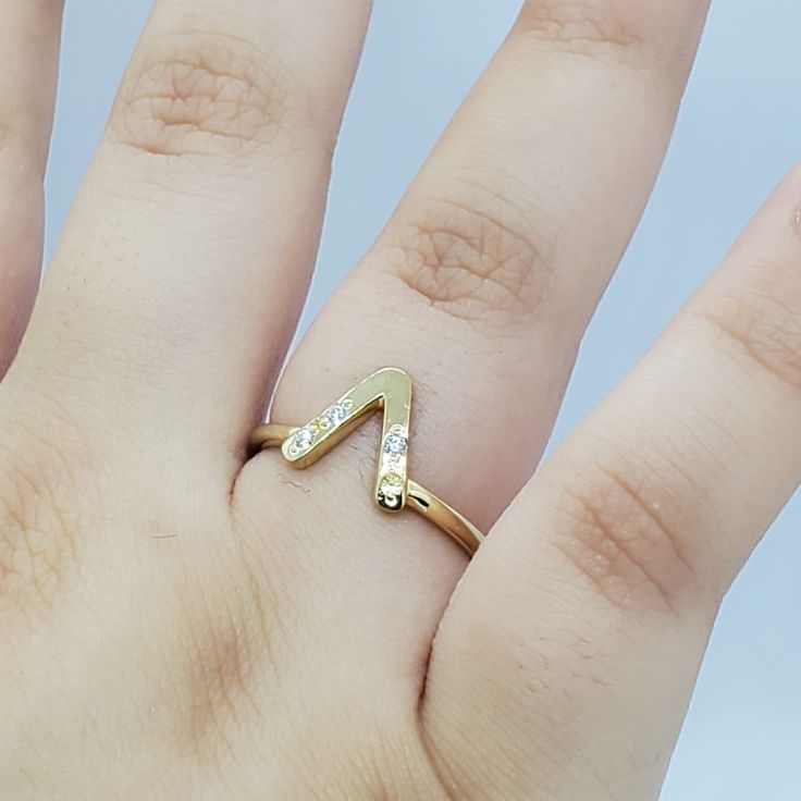 a person's hand with a gold ring on top of it and two diamonds in the middle