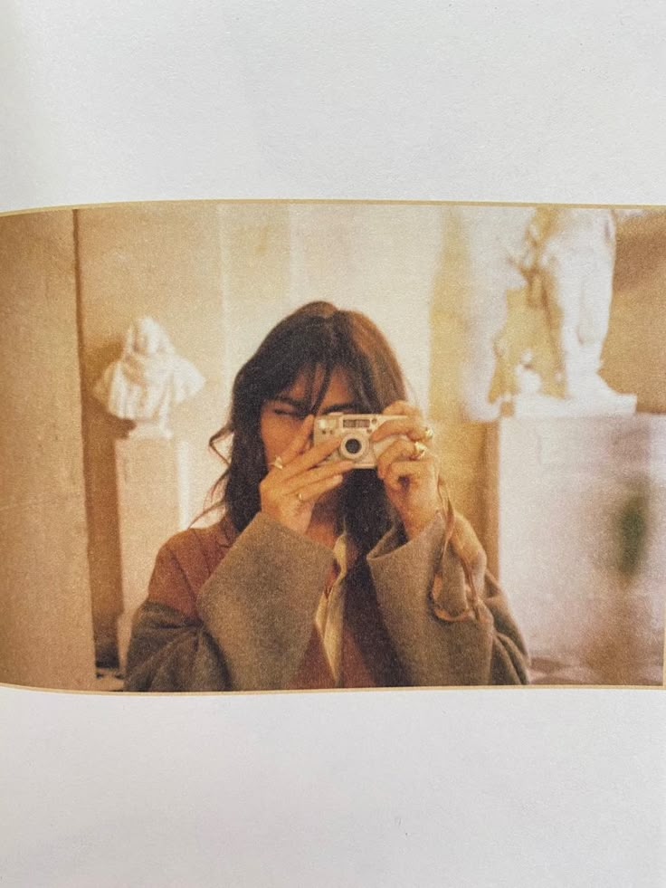 a woman taking a selfie in front of a mirror while holding a camera up to her face