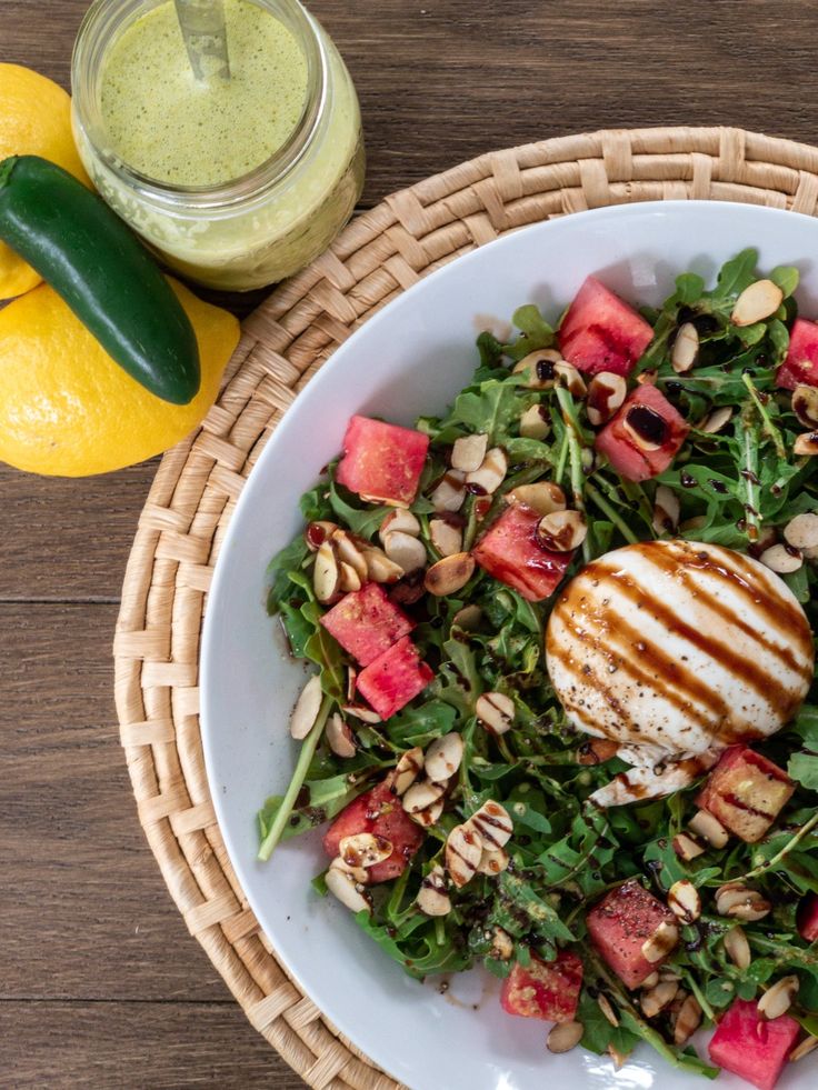 a salad with grilled chicken, watermelon and almonds on a white plate