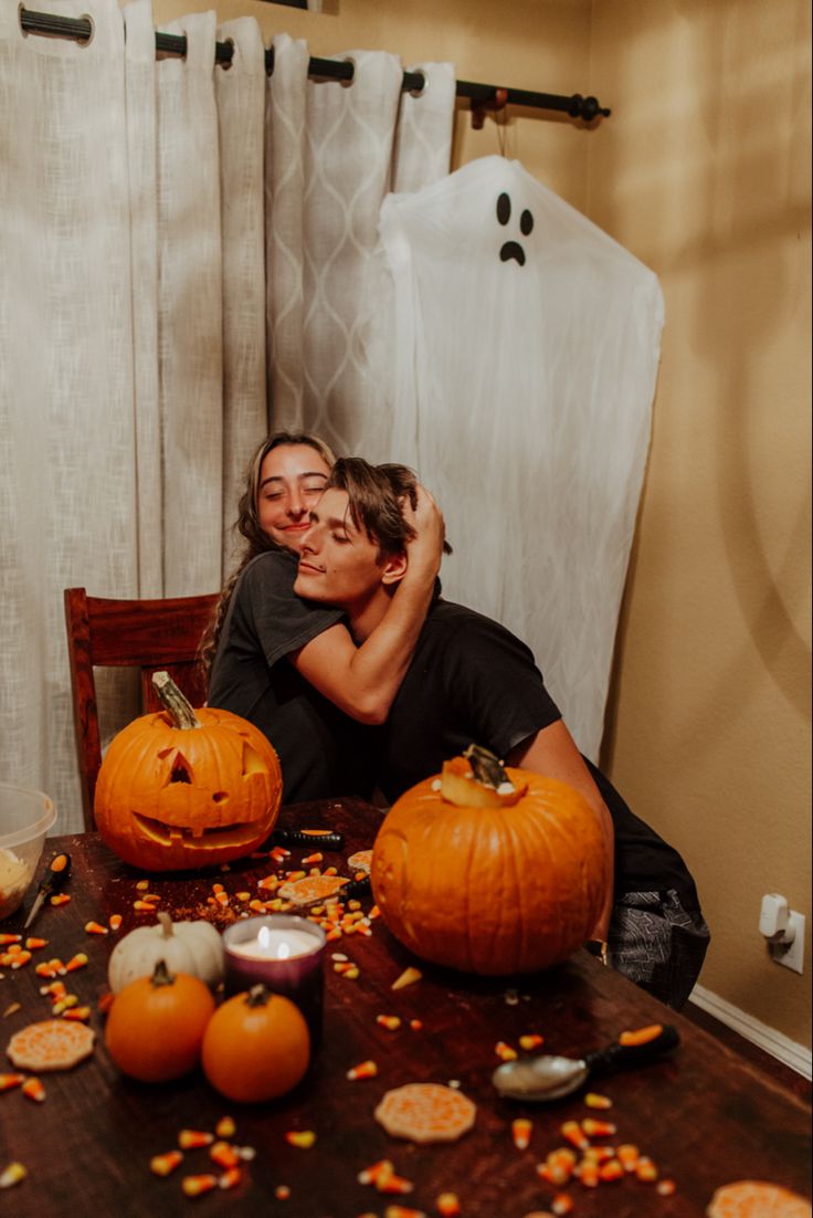 two people sitting at a table with pumpkins