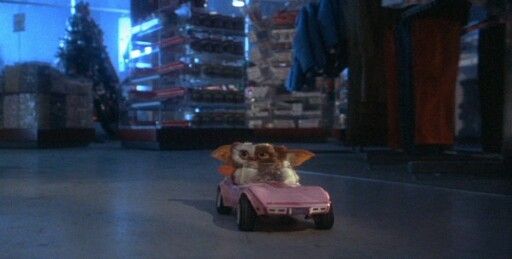 a small dog sitting on top of a pink toy car in a room filled with boxes