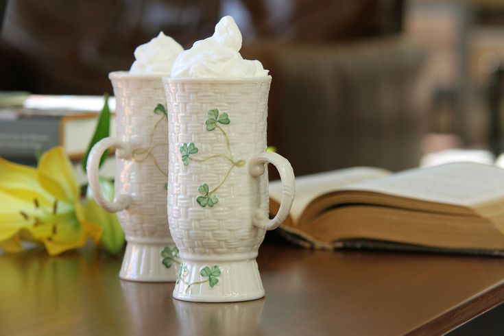 two mugs with whipped cream on them sitting on a table