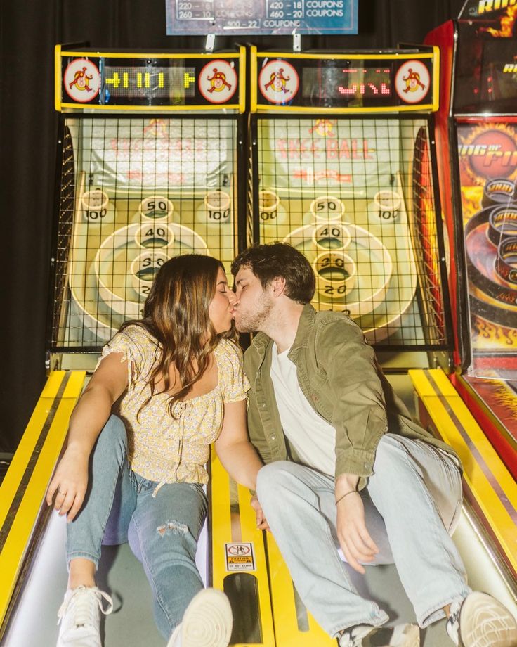 a man and woman kissing in front of two pinball machines