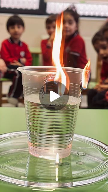 a cup with fire in it sitting on top of a green table next to other children