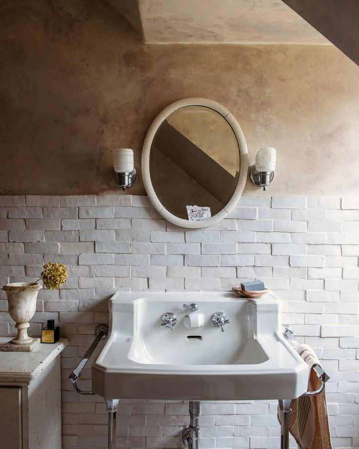 a white sink sitting under a bathroom mirror next to a wall mounted faucet