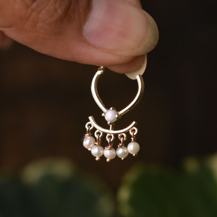 Throughout the centuries, pearls have been associated with wealth, femininity, purity, wisdom, patience and peace. Due to their appearance, they have often been compared to the moon, and are said to have a calming, protective and strengthening effect on the wearer. This unique septum clicker is crafted in solid 14k or 18k gold, with dangling pearls. It is a unique addition to our collection and will be for your setup too. This hinged clicker would make a lovely helix earring too. VERTICAL INNER Elegant 14k Gold Nose Ring As Gift, Elegant Hoop Nose Rings Gift, Elegant Wedding Septum Ring, Elegant Hoop Septum Ring For Anniversary, Elegant Gold Septum Ring For Gift, Elegant 14k Gold Septum Ring For Anniversary, Elegant Rose Gold Septum Ring For Wedding, Elegant 14k Gold Round Septum Ring, Heirloom Round Pearl Drop Jewelry