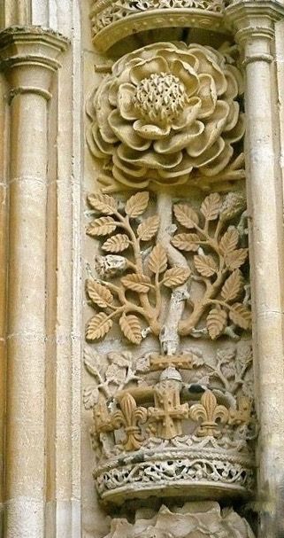 an ornate carving on the side of a building with flowers and leaves growing out of it