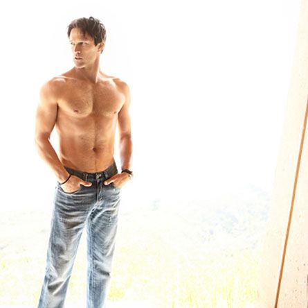 a shirtless man standing in front of a window with his hands on his hips