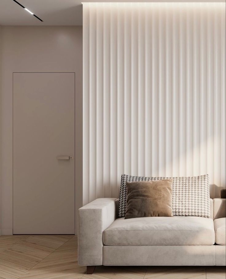 a white couch sitting in front of a wall with vertical blinds on it's side