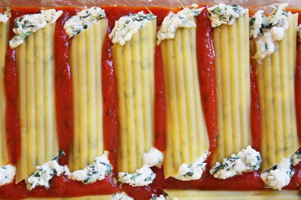 several slices of ravioli with cheese and sauce on them in a rectangular pan, ready to be cooked