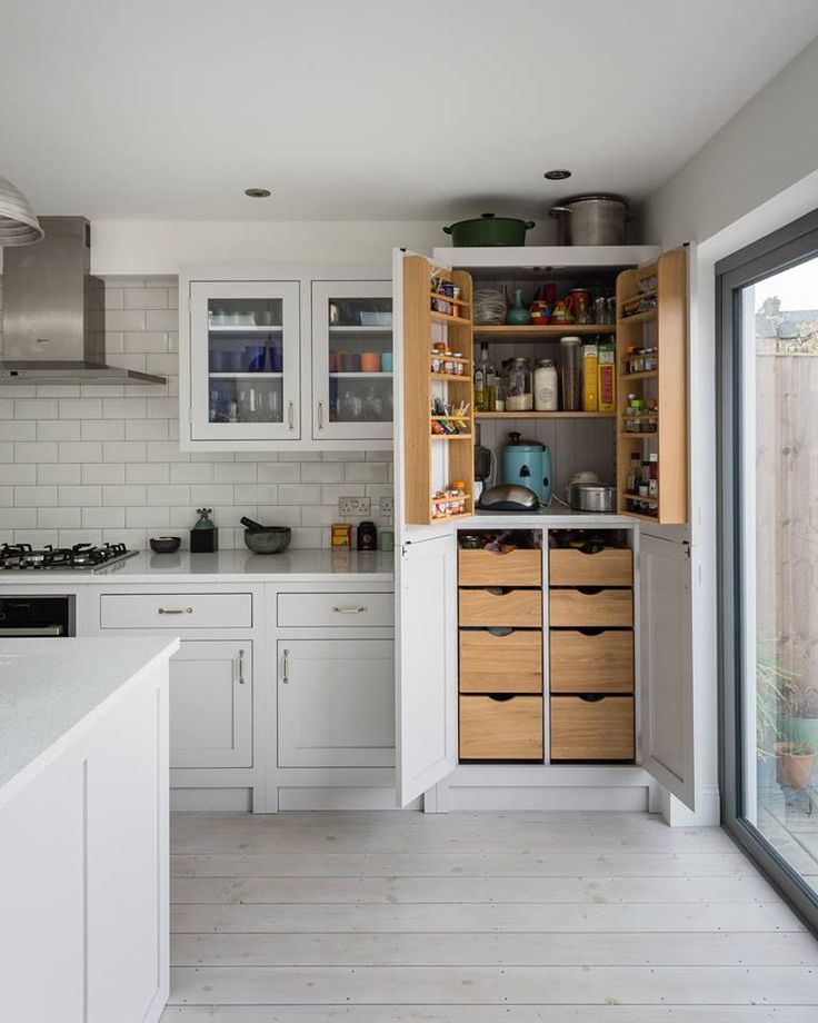 a kitchen with white cabinets and wooden drawers