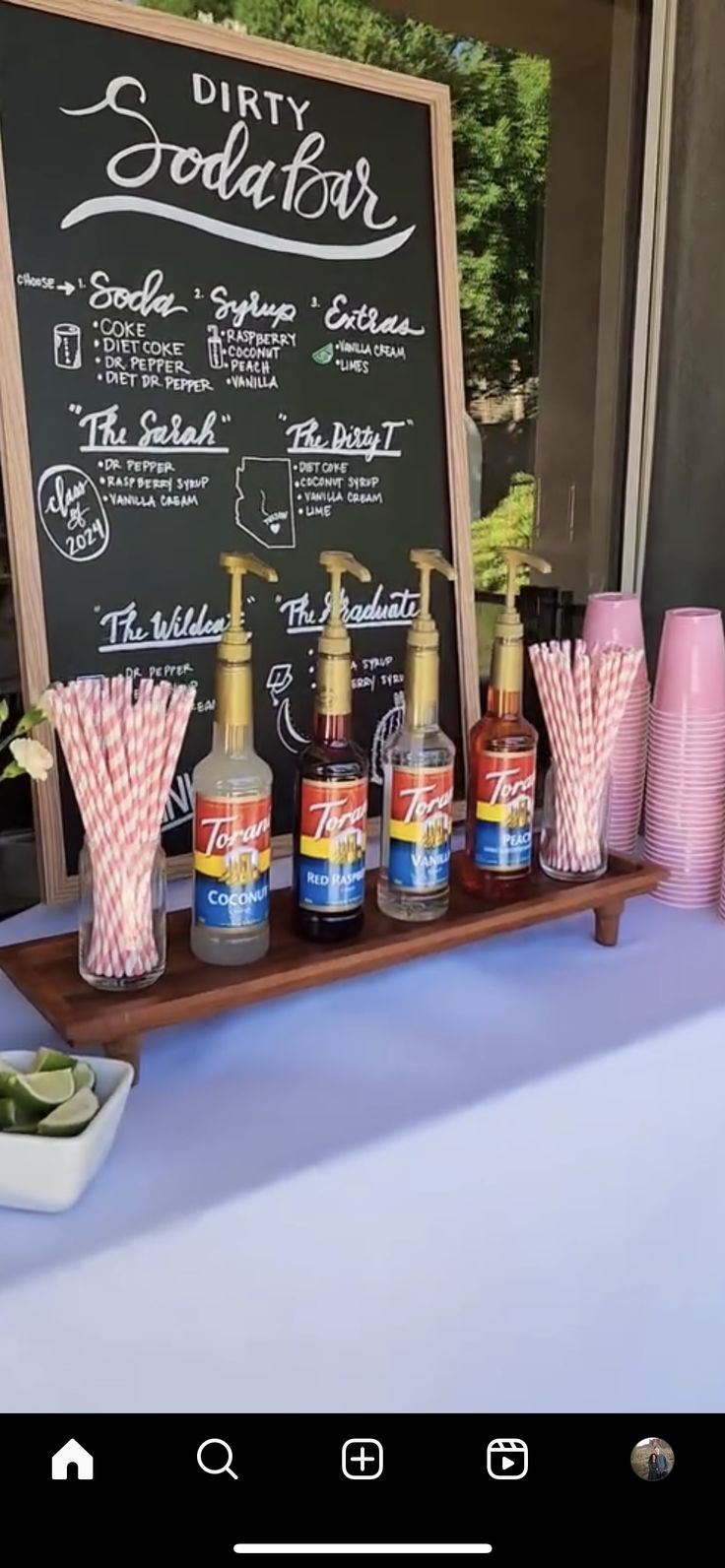 a table topped with bottles and cups filled with liquid next to a chalkboard sign