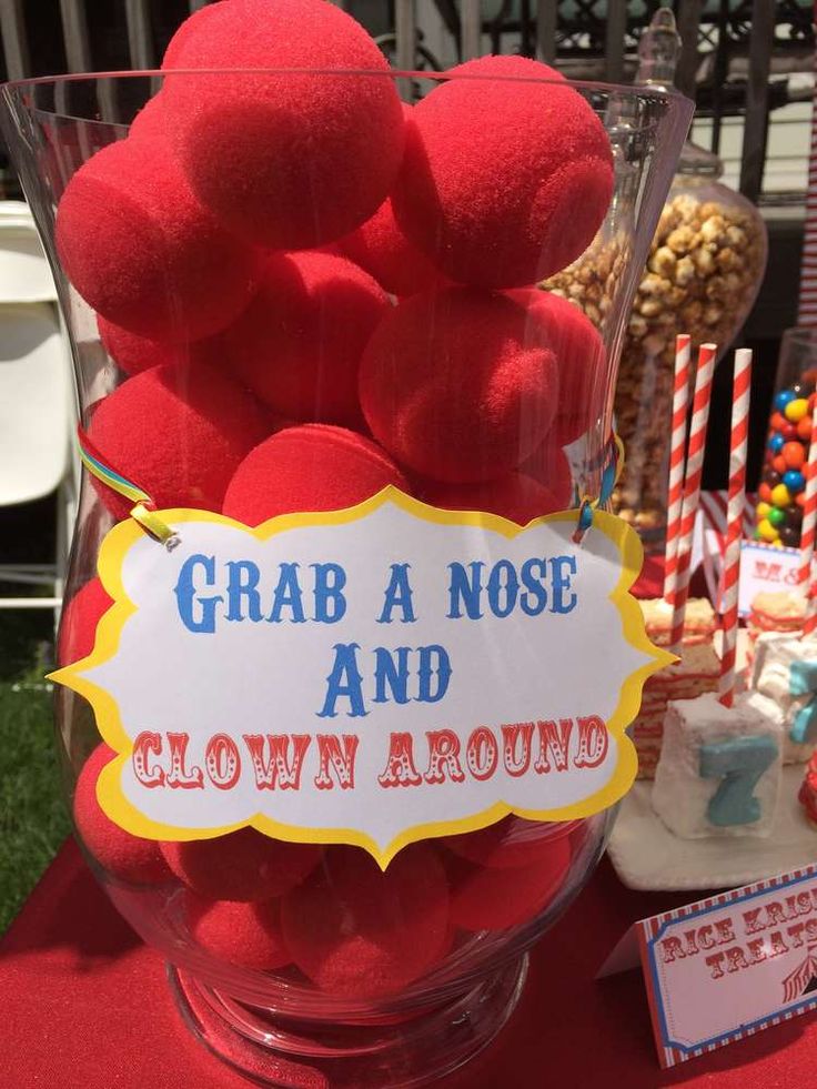 a glass vase filled with lots of red pom - poms and a sign that says grab a nose and clown around