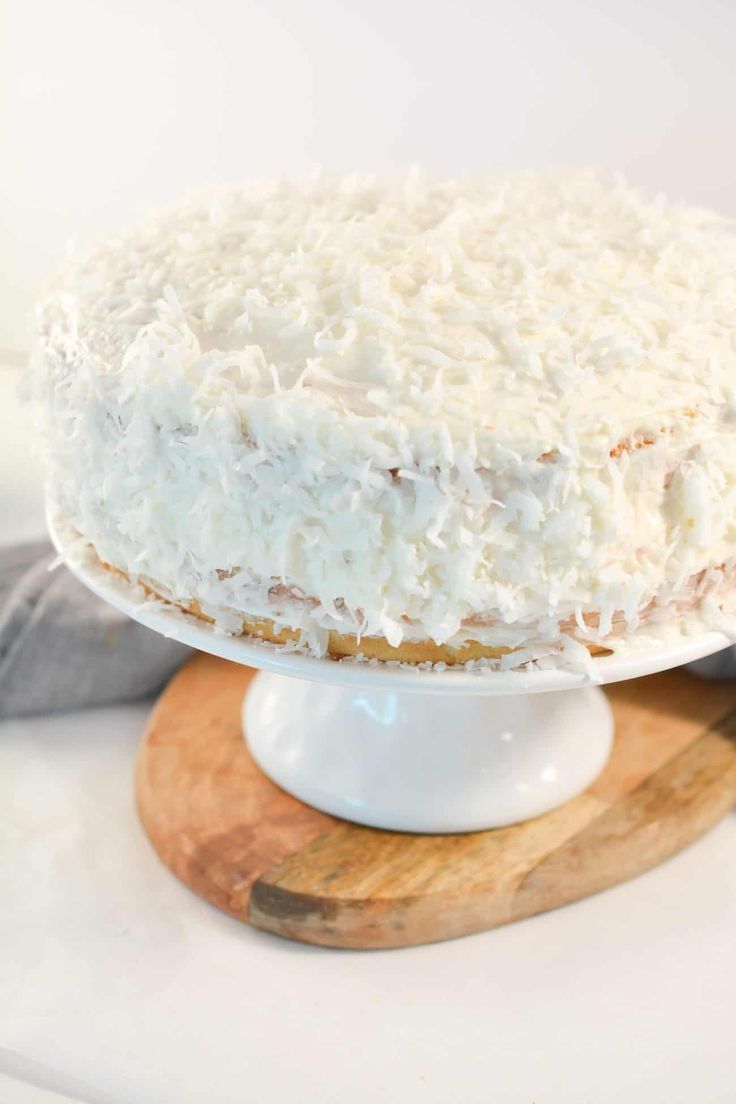 a cake with white frosting sitting on top of a wooden stand