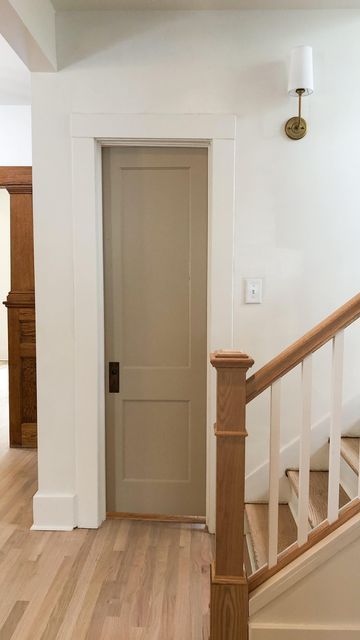 an open door in the middle of a wooden floored hallway with white walls and wood handrails