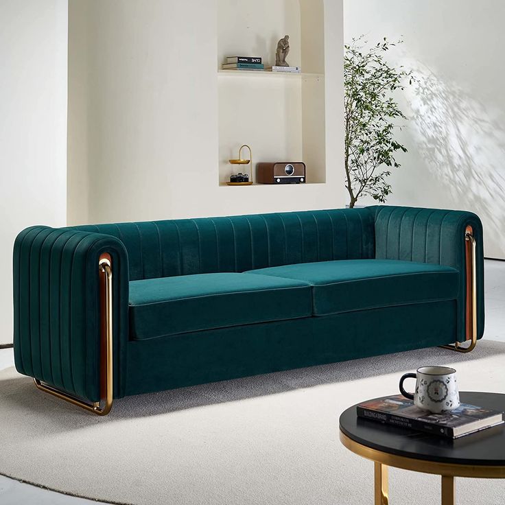 a living room with a green velvet couch and coffee table in front of the wall