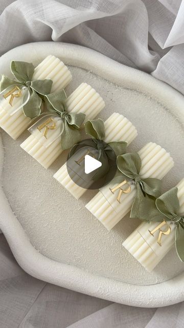 four pieces of white chocolate with green leaves and ribbons on top of a platter