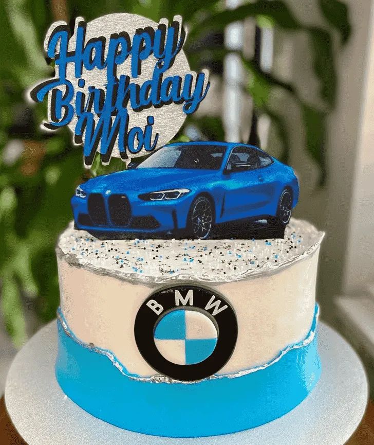 a birthday cake with a blue bmw car on it's top and the words happy birthday moi