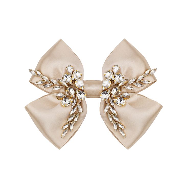 a pair of hair clips with bows and crystals on top of each one in beige