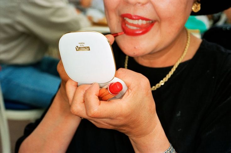 a woman is holding a small electronic device in her hand and smiling at the camera